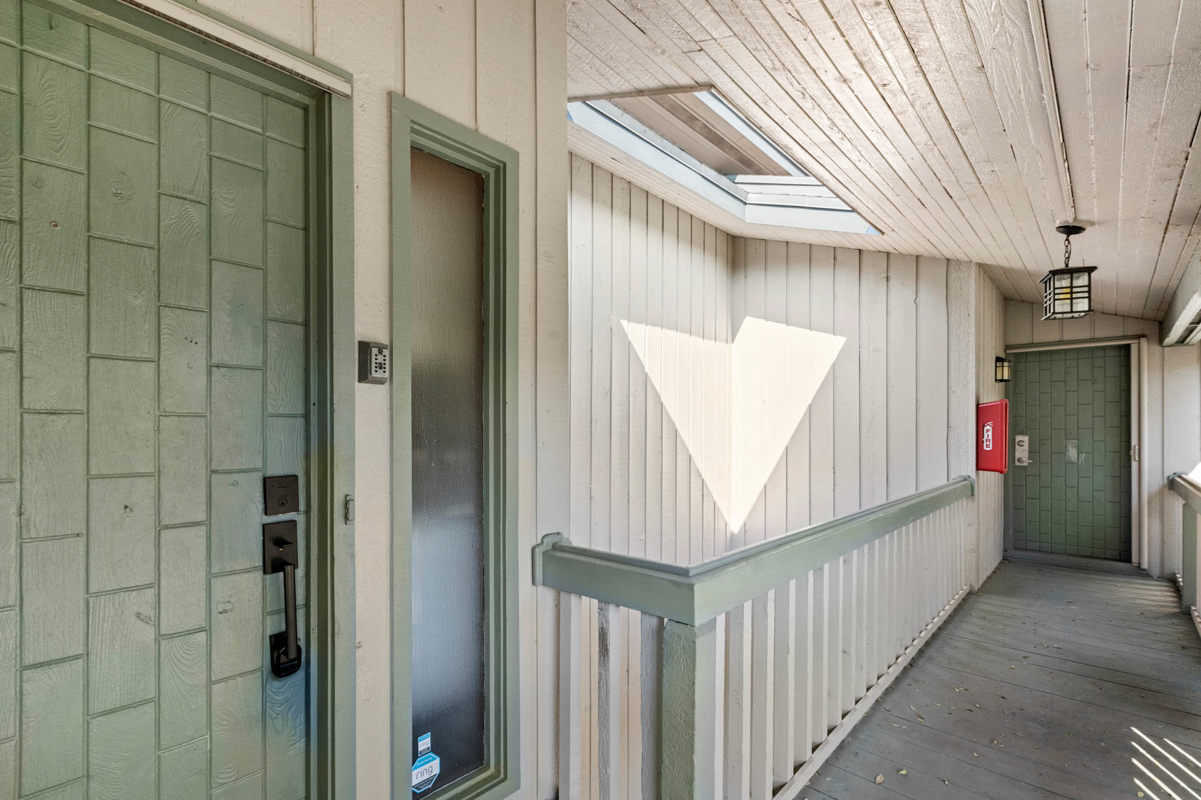 two exterior green doors with cement ground hallway